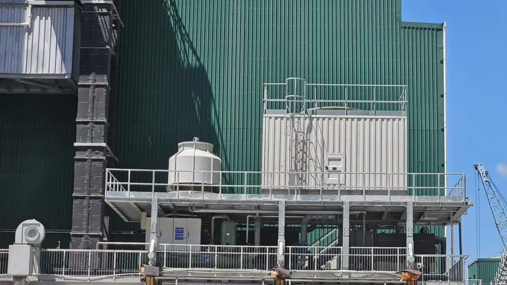 Elevated industrial chilled-water equipment beside a green-clad plant building in Hong Kong