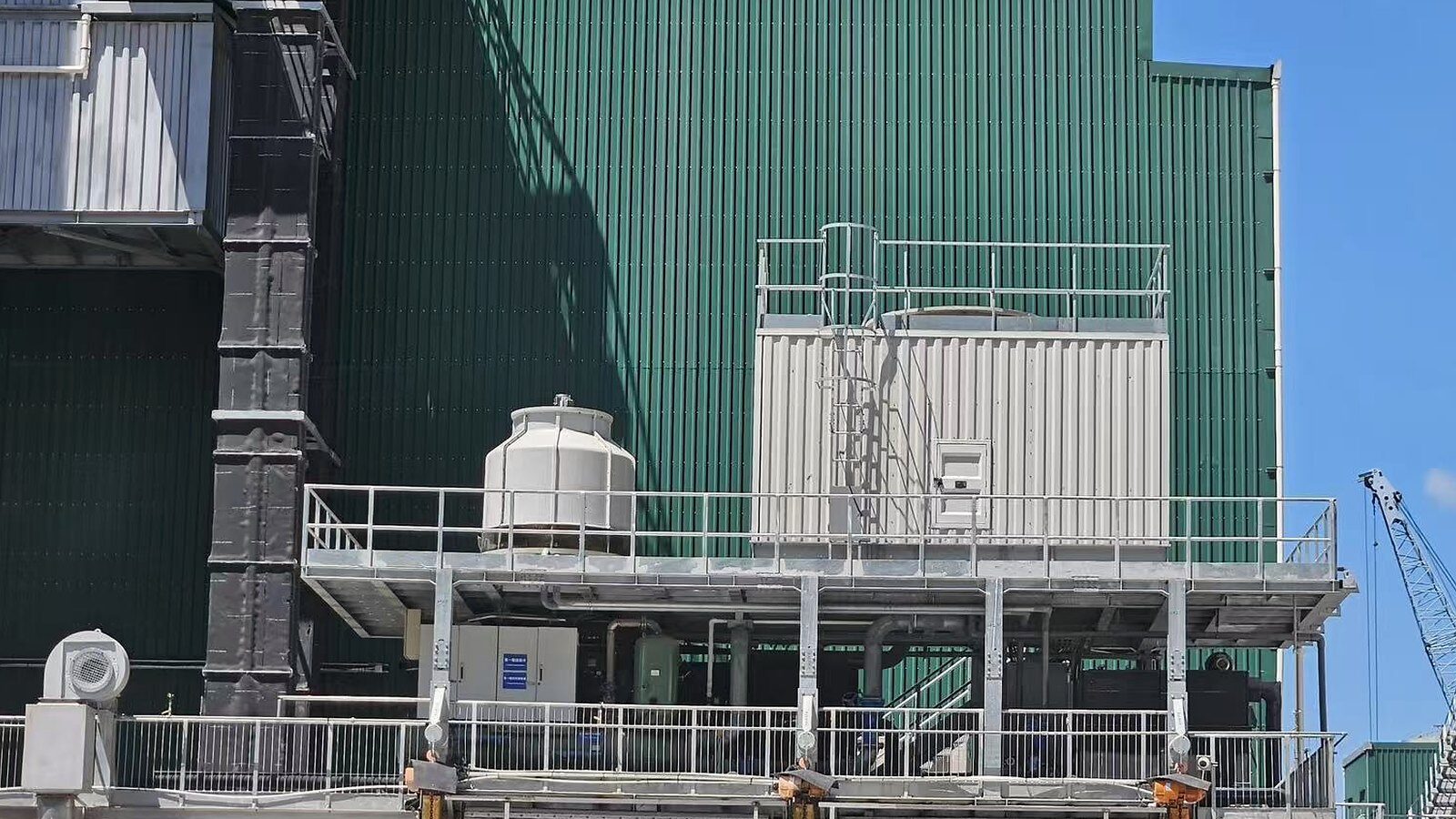 Elevated industrial chilled-water equipment beside a green-clad plant building in Hong Kong