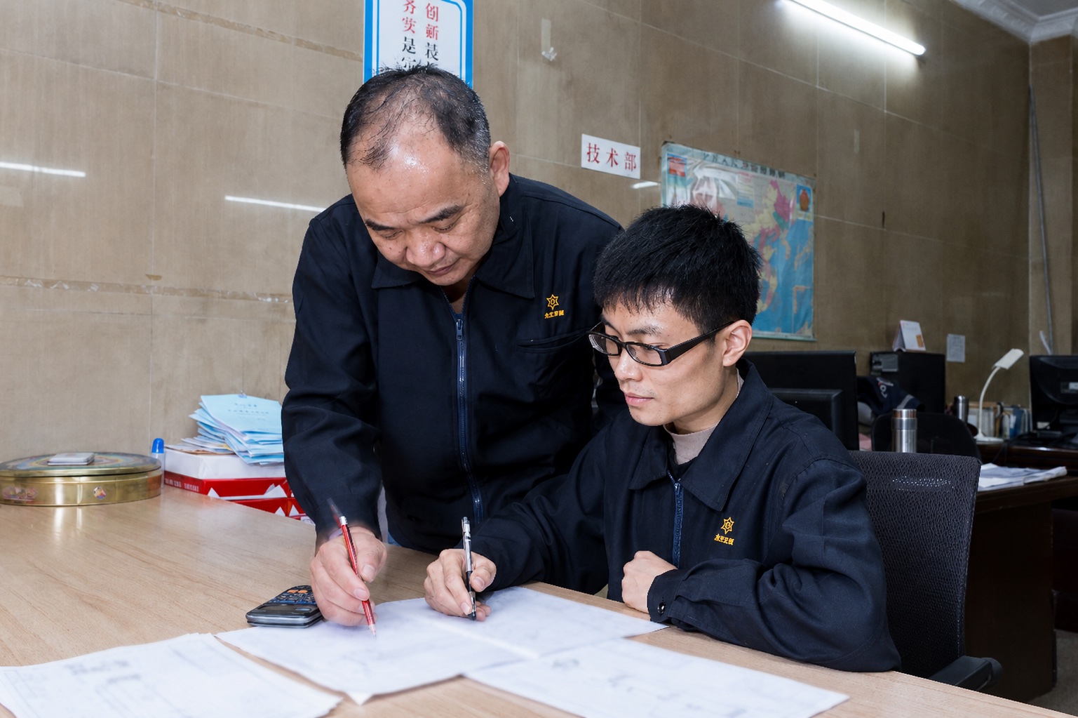 Two Jinduo team members reviewing engineering drawings at the former Foshan operations.