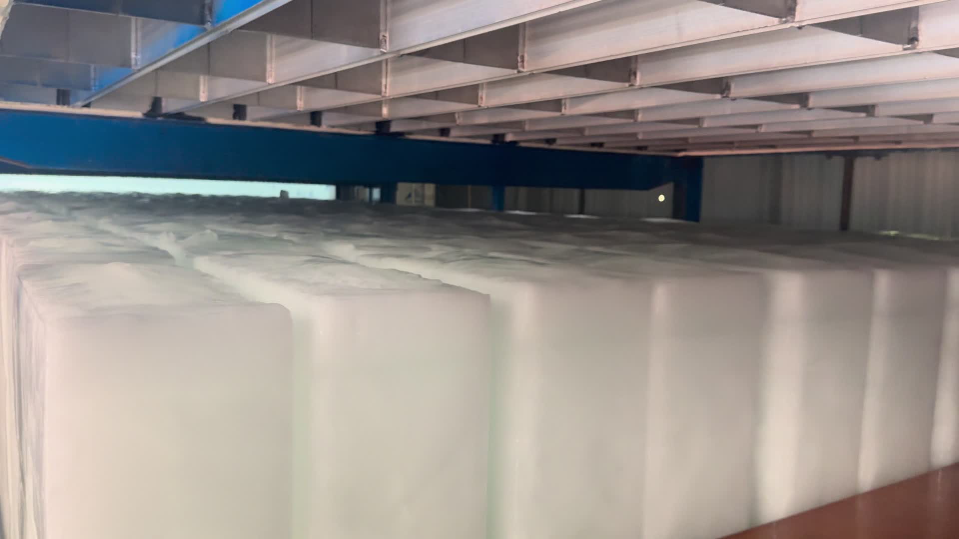 Rows of freshly released ice blocks below the block ice machine